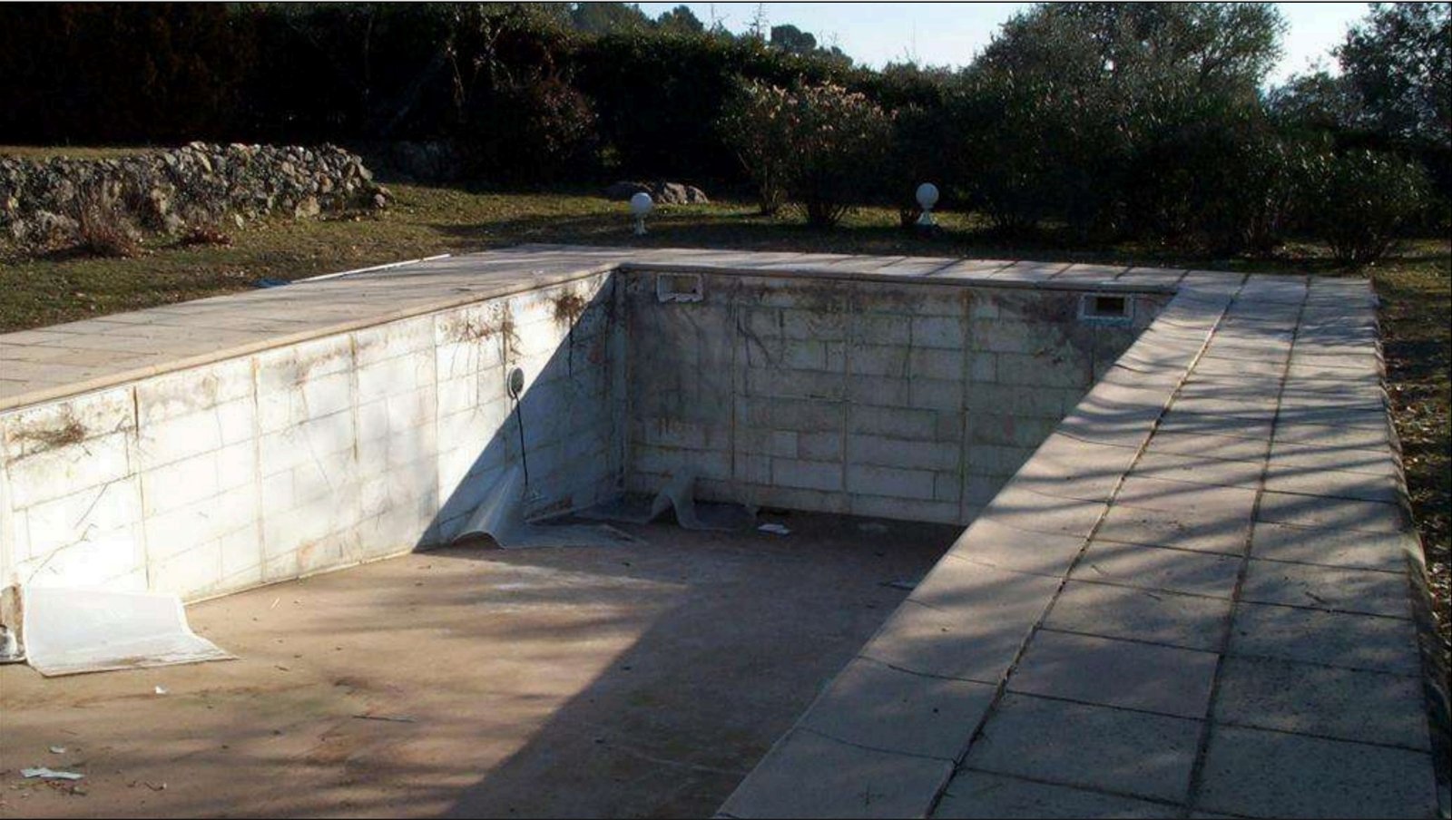 Ancien bassin de piscine avec ses parois mises à nu